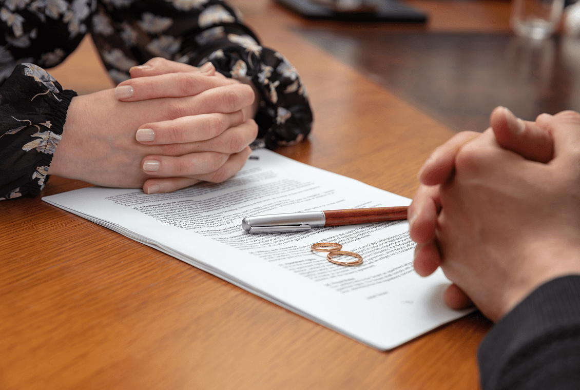 Hands over divorce papers with wedding rings