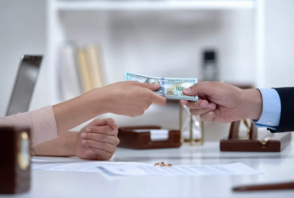 Hands passing a hundred-dollar bill